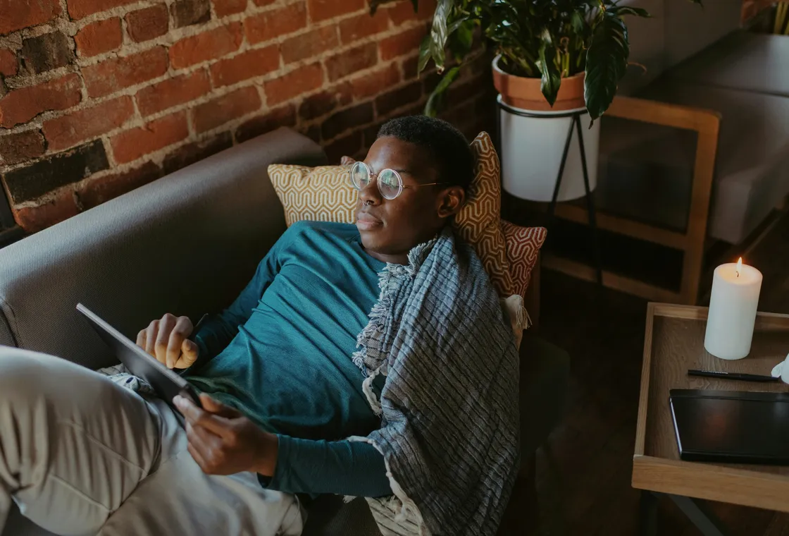 A man sitting quietly with a tablet in a calm, softly lit room