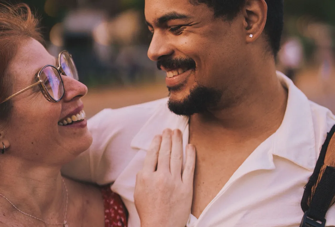 A couple facing each other and laughing together outdoors
